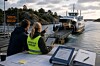 To personer sitter ved et bord og ser mot en bilferje som legger til ved kaia.