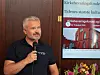 Mann holder mikrofon ved en skjerm som viser en presentasjon om kirkebevaringsfondet.