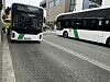 To hvite og grønne bybusser kjører på en bygate.