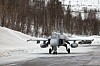 Svensk Saab JAS 39 Gripen taxer mot kamera på en snødekt rullebane.