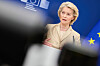 Ursula von der Leyen taler foran EU-flagg og en blå bakgrunn.