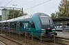 Grønt Vy-tog står ved en jernbaneplattform.